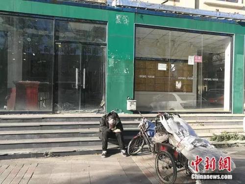 资料图：2018年10月，燕郊“售楼一条街”，已经关门的链家门店前停着一辆装货的三轮车，车的主人坐在地上，把头深深地埋进臂弯。