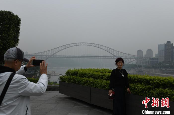 图为重庆主城遭遇大雾天气，市民在岸边围栏处拍照玩耍。周毅 摄