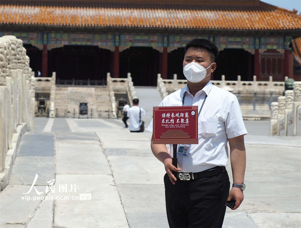 2022年6月7日，故宫博物院内，工作人员手持防控提示牌，提醒游客做好防护。