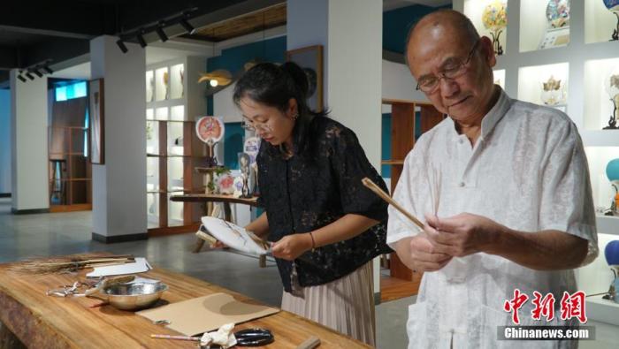 图为10月21日，桂林团扇制作手艺人黄硕夫(右)和女儿黄可人(左)共同制作团扇。 <a target='_blank' href='/'>中新社</a>发 李娇阳 摄 　