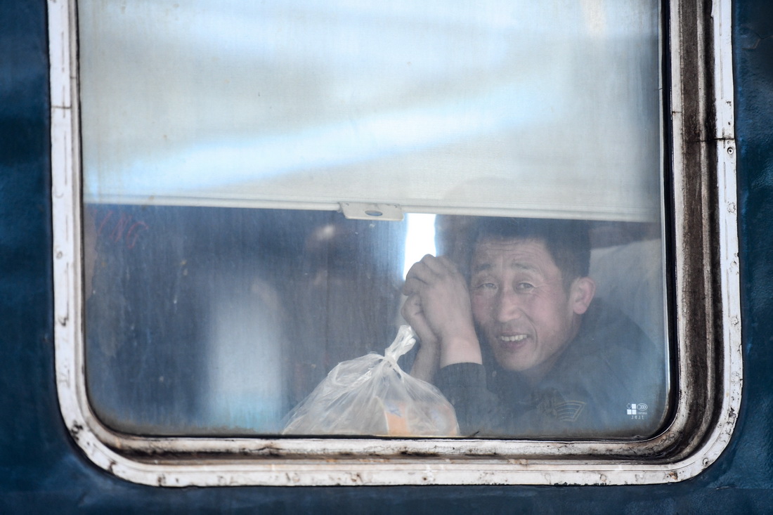 在K5151次列车车厢中，一位乘客在座位上望向窗外（5月6日摄）。