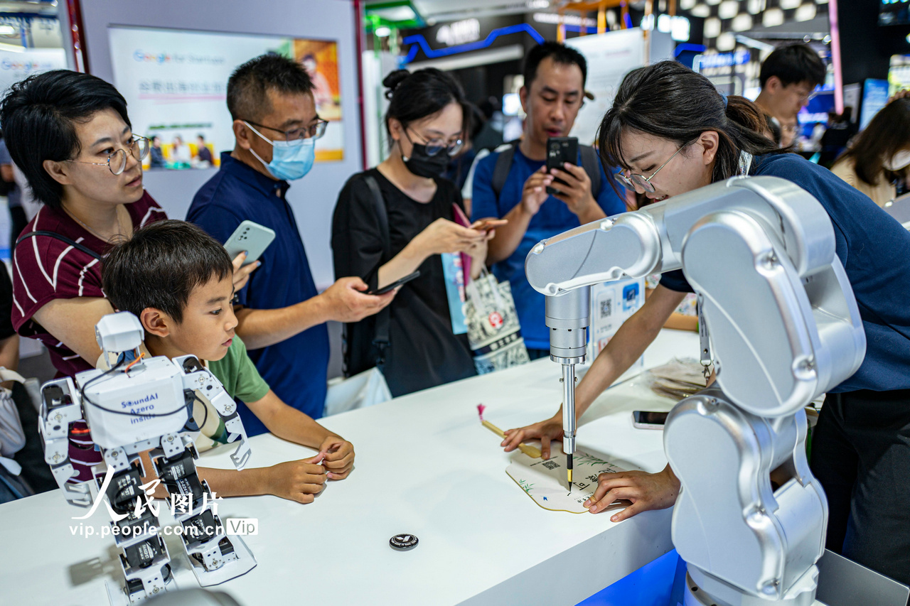 7月6日，2023世界人工智能大会现场，观众在围观机械臂展示AI书法写作。