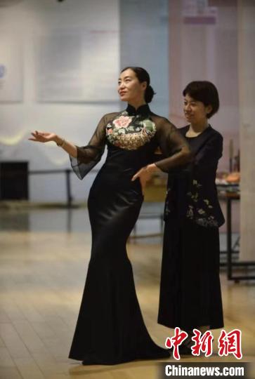 张丽娟(右)正在给旗袍爱好者试穿新创作的服饰作品。陈璐 摄